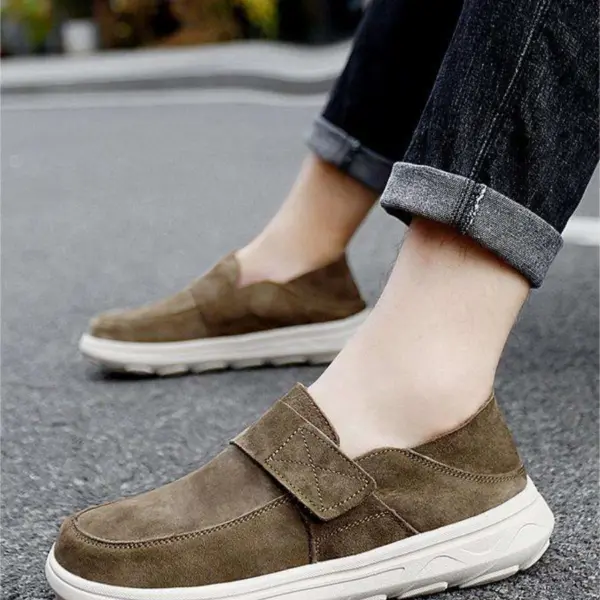A person wearing rolled-up jeans and New Retro Men Shoes Light Shock Absorbing Flat Sneakers Wholesale Customized Leather Loafers with white soles stands on a paved surface.
