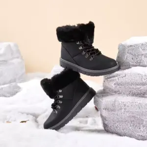The 2025 Colorful Boots Women Shoes, fashion faux suede plush snow outdoor warm ankle boots for ladies, are shown in black with fur lining and metal eyelets, available for OEM/ODM orders, displayed on artificial rocks and snow.