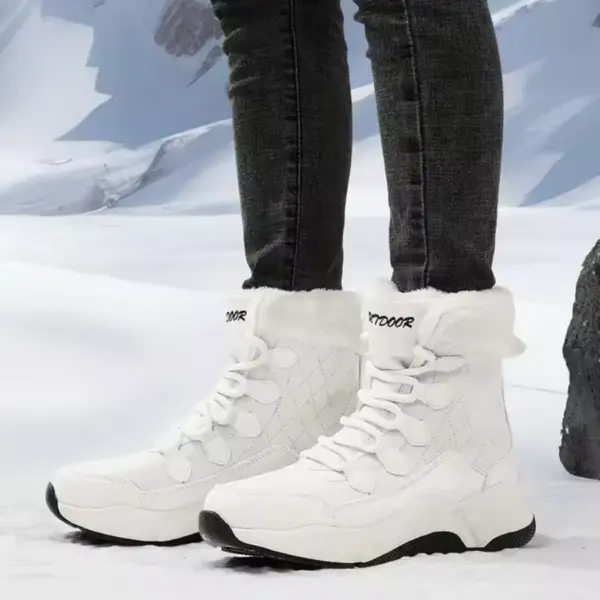 A person in white OEM ODM Source Factory Winter Waterproof Anti slip Warm Snow Boots Women's Solid PU Cotton Shoes and black jeans stands on snow before mountains, showcasing the boots' quality.