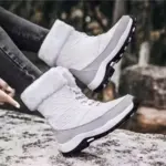 A woman wears OEM Factory High Top Breathable Warm Cotton Snow Boots—winter outdoor laced PU shoes—standing on a snowy surface.