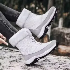 A woman wears OEM Factory High Top Breathable Warm Cotton Snow Boots—winter outdoor laced PU shoes—standing on a snowy surface.