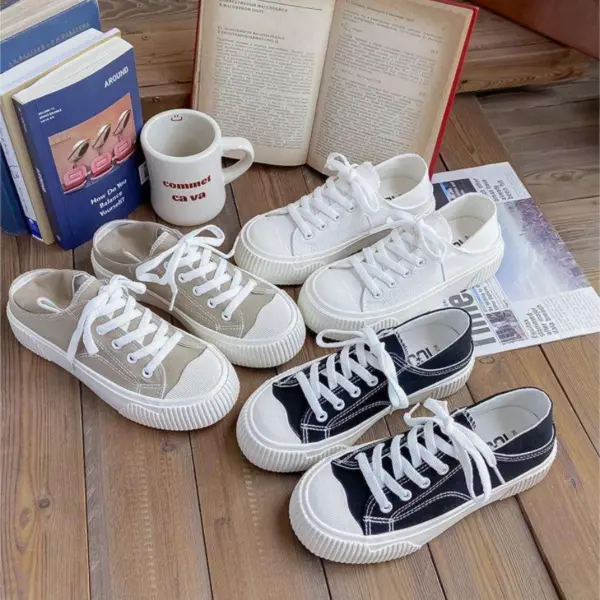 Three pairs of Breathable Designed Women Shoes Solid Cotton Sneakers Slip on Low Top Women Canvas Shoes in beige, white, and black are displayed on a wooden floor beside books, magazines, and a coffee mug, offering stylish and versatile everyday options.