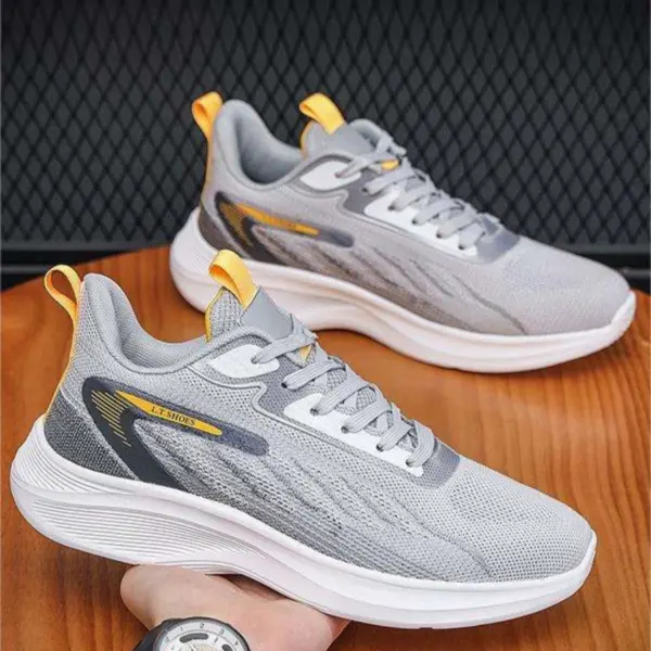 Light gray men's shock rebound running sneakers with white soles, yellow accents, and mesh uppers—ideal for OEM/ODM customization. Wholesale custom outdoor light breathable sport shoes displayed on a wooden surface.
