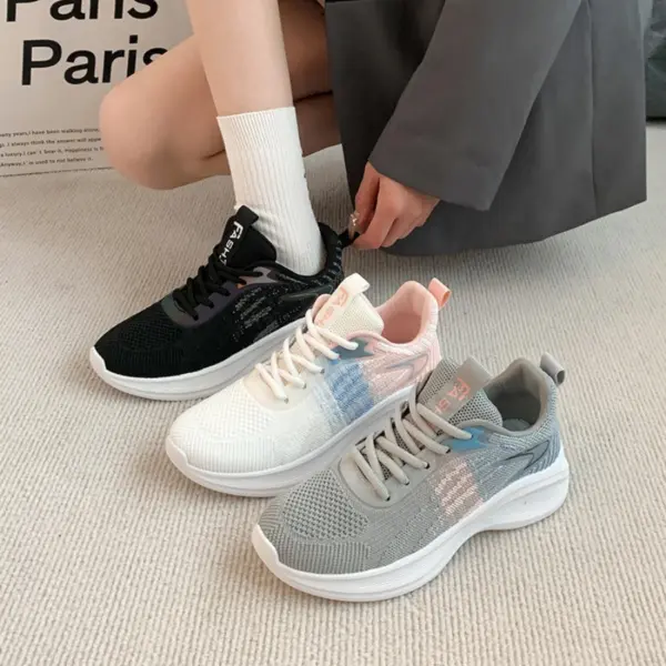 A person in a grey outfit and white socks is putting on a black Factory Custom Spring New Styles Sports Sneaker. Two more sneakers, one white and one grey, are on a beige carpet.