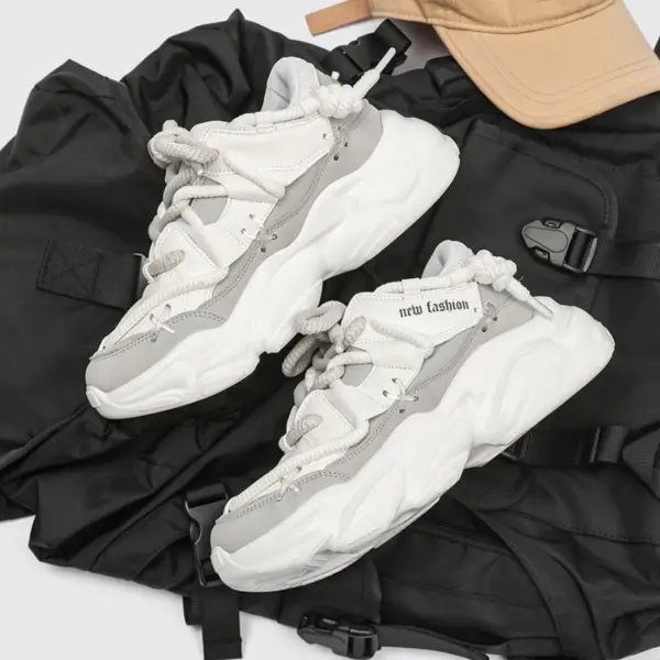 A pair of 2024 Fashion Breathable Mesh Casual Sports Running Sneakers for Men with thick soles in white and gray are placed on a black backpack next to a beige cap.