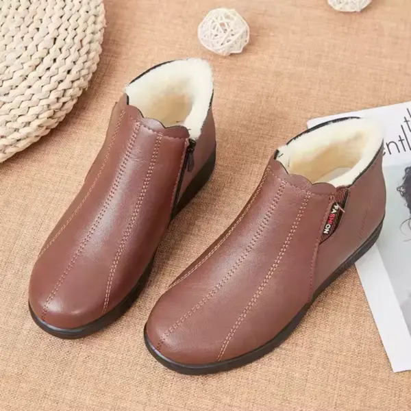 A pair of Women Shoes Snow Boots: waterproof winter leather ankle boots with side zippers, white cotton fur lining, and non-slip soles, displayed on a beige fabric surface beside a magazine and decor.