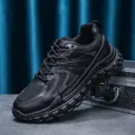 The OEM Trendy Tire Sole Men's Light Anti-slip Wear Resistant Sneaker, made of cotton mesh and EVA, is shown in black on a gray surface next to a metallic case, set against a blue curtain background.