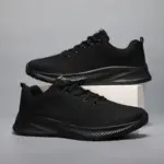 A pair of Men's Casual Sneakers featuring black flying weaving mesh uppers and lightweight EVA soles, displayed on a plain gray background with one shoe resting on a white block.