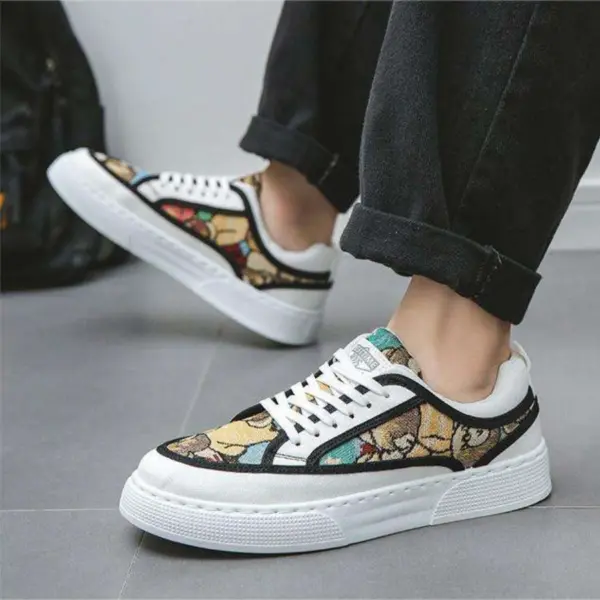 A person in black pants wearing Wholesale Factory 2024 Rubber Embossing Canvas Shoes—laced, multicolored with a leaf pattern, white soles and laces—stands on a gray floor.
