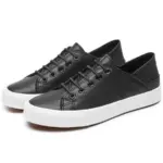 A pair of Fashion Low Top PU Upper Black Walking Canvas Sneakers for Women with white rubber soles and black laces, displayed side by side on a white background—ideal for OEM or ODM customization.