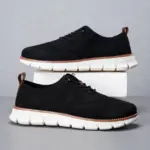 Big Size Men's lace-up lightweight breathable sports shoes with hollow-out flying weaving design and EVA sole, perfect for OEM/ODM orders—featured in black with white thick soles and brown accents against a neutral background.
