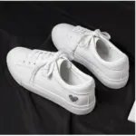 A pair of Xrh Wholesale Spring PU Valentine's Day Gift Love Custom Low Top Vulcanize White Shoes for women, featuring a small heart on the heel, displayed on a black surface.