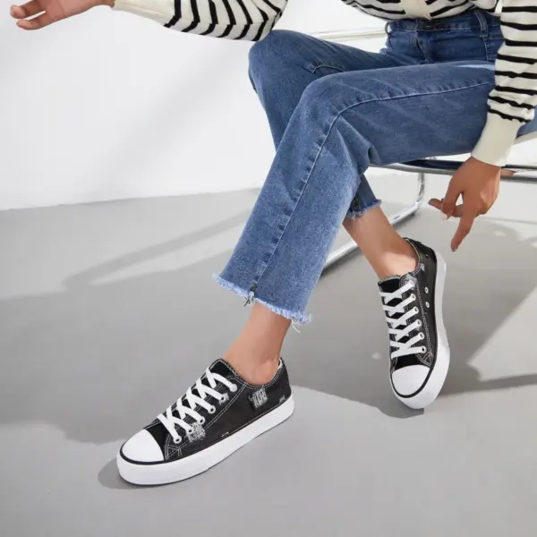 A person sits on a chair wearing blue jeans, a striped sweater, and Wholesale Custom Made Blue Walking Style Canvas Shoes Women's Casual Canvas Shoes for Ladies and Women New Style.