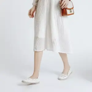 A person in a textured white dress and Office Round Toe Dress Flat Shoes holds a small brown handbag, standing against a plain white background—ideal for OEM ODM fashion showcases.