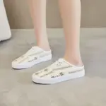 Person wearing XRH Wholesale rubber casual shoes—custom logo, half-top print canvas slippers for women—in white with floral patterns, standing on a light-colored floor.