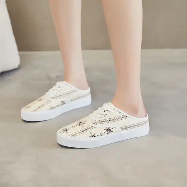 Person wearing XRH Wholesale rubber casual shoes—custom logo, half-top print canvas slippers for women—in white with floral patterns, standing on a light-colored floor.