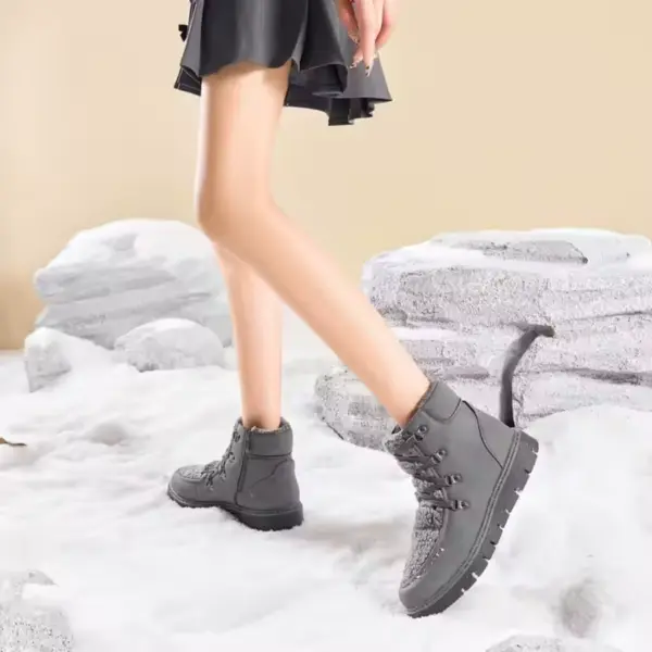 A person wearing black leather high top flat heel ladies boots walks on snow with rocks in the background, highlighting Low Price Shoes Women Black Leather Boot for Winter Wear—perfect wholesale footwear for winter collections.