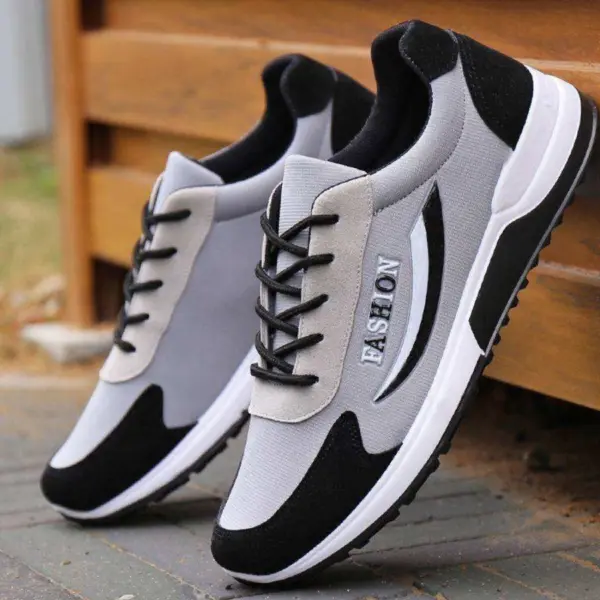 A pair of High Quality Gym Casual Cushioning Sneakers for men in gray and black, with "FASHION" on the side, displayed outdoors near a wooden structure.