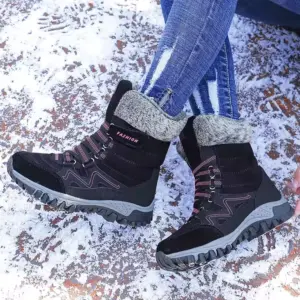 Person wearing Wholesale Customizable Leather Warm Women Snow Boots, featuring breathable rubber soles and lace-up cotton design, sitting on snow in ripped blue jeans—ideal for highlighting OEM ODM footwear styles.