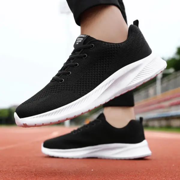 A person wearing Men's Casual Sneakers Flying Weaving Light Weight Lace-Up Black Mesh Breathe EVA Sole Sports Shoes stands on a red running track.