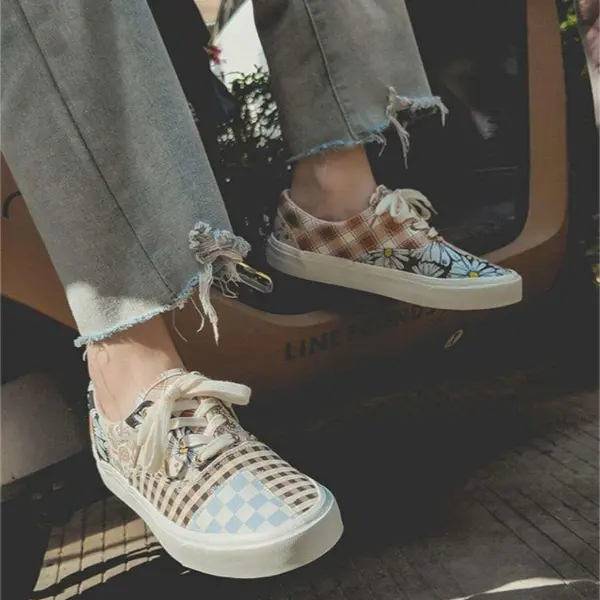 A person in frayed hem jeans and Wholesale Mixed Wearable Canvas Shoes—lace-up, breathable low-top canvas sneakers—sits on a ledge.