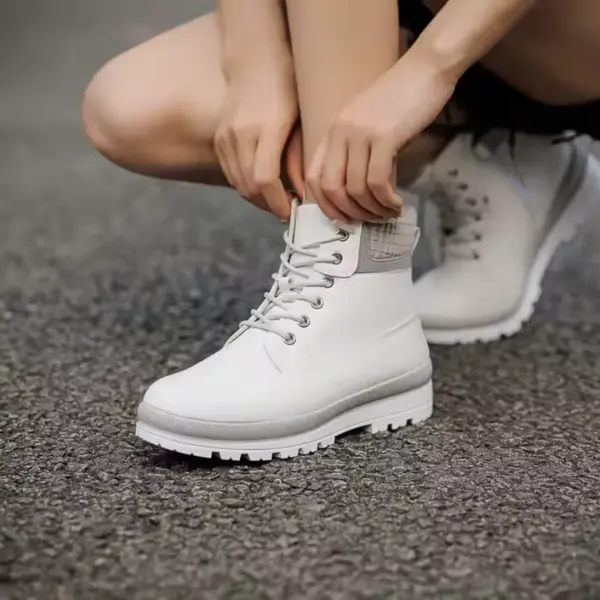 A person squats on asphalt while tying the laces of 2025 New Arrivals Winter Snow White Boots for Women Men, custom height-increasing lace-up leather boots.