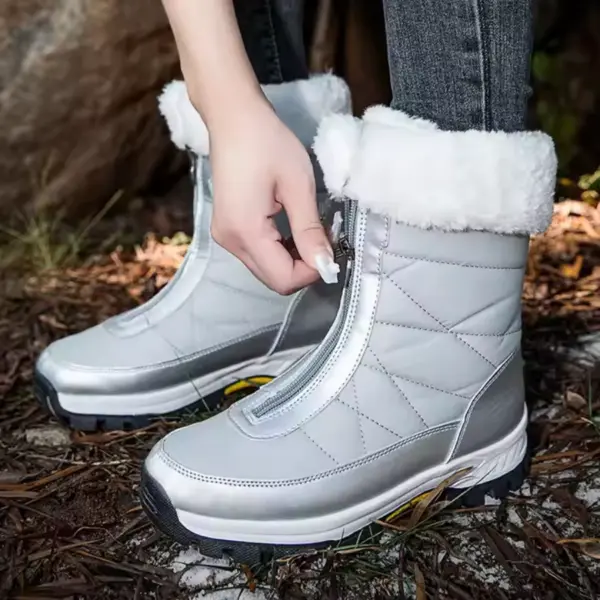 A person zipping up Wholesale Custom Winter Trendy Waterproof Snow Boots with plush lining stands outdoors on dry leaves and pine needles.