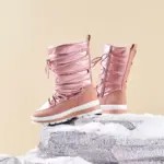 A pair of high quality winter platform mid calf boots with chunky heels and round toes in metallic pink, featuring side zippers and white soles, displayed on snowy rocks against a beige background.