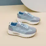 A pair of OEM ODM Durable Wearable Breathable Low Top Sneakers for women with white soles and blue laces, designed for outdoor walking, displayed on a beige surface.