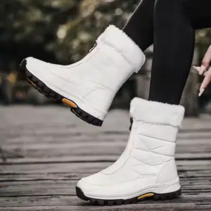A person wearing 2025 Spring Wenzhou Factory Zipper Women Casual Waterproof Fur Winter Outdoor Medium Snow Boots, featuring stylish fur trim and black soles, sits outdoors in black leggings—perfect for showcasing chic footwear.