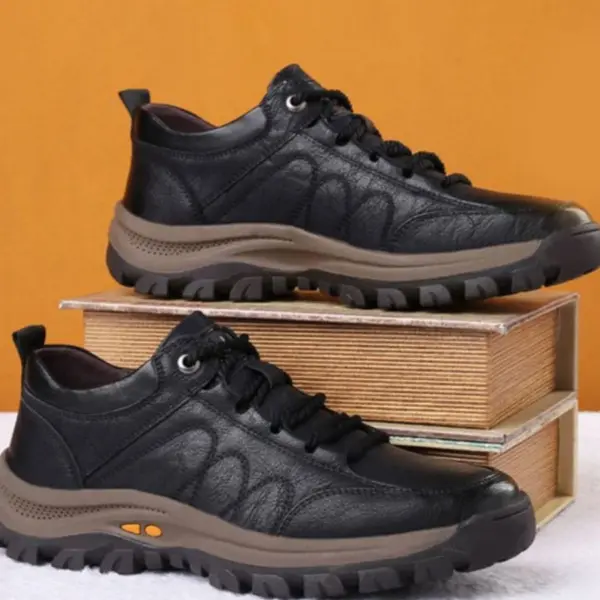 A pair of Men's Solid Faux Leather Lace Up Sneakers with durable brown soles, made by an OEM ODM manufacturer, displayed atop two stacked books against an orange background.