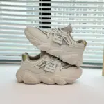 A pair of Women's Low Top Mesh Thick Sole Height Increasing Wear Resistant Outdoor Sports Sneakers are stacked on a tabletop in front of a window with horizontal blinds.