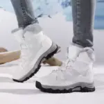 A person wearing light gray Custom Factory Style Winter Mid Top PU Women Snow Boots with thick soles and plush lining stands on snow with a blurred outdoor background.