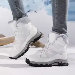 A person wearing light gray Custom Factory Style Winter Mid Top PU Women Snow Boots with thick soles and plush lining stands on snow with a blurred outdoor background.