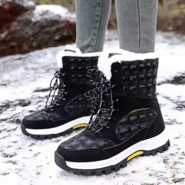 A person stands on snowy ground wearing grey pants and 2024 Customized LOGO Pattern Style Autumn Winter Trendi Warm Snow Boots Mixed PU Cotton Shoes in black and white with fur lining.