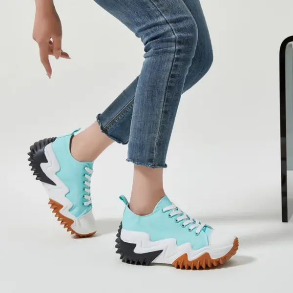 A person wearing XRH Wholesale Plain Casual Custom Logo Mujer Ladies Sneakers—trendy blue and white canvas shoes with thick, ridged black and brown soles—paired with blue jeans, poses by a black chair leg on a white background.