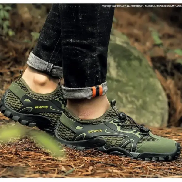 A person wearing green and black OEM ODM Wholesale Customized Outdoor Hollow Mesh Hiking Shoes with "Mashion" branding stands on a forest floor in rolled-up jeans, highlighting the shoes' anti-slip EVA rubber soles and breathable comfort.