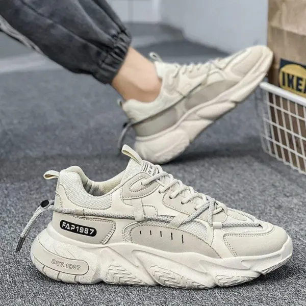 A pair of beige Factory Wholesale OEM ODM Summer Mesh Sneakers for men with decorative labels and stitching, shown on a gray carpet—one worn, one on display—highlighting customizable anti-slip outdoor PU rubber sports shoe options.