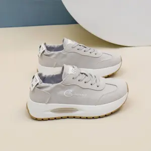 A pair of OEM ODM Durable Wearable Breathable Low Top Sneakers for women, in light gray with white soles and beige outsoles, "Guixing" on the sides, perfect for outdoor walking and customization, displayed on a neutral background.