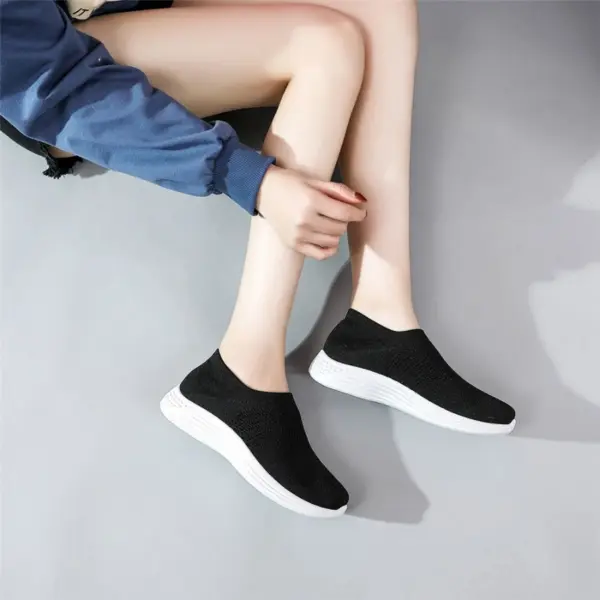 Person sitting on a gray floor, wearing a blue jacket and High Quality Brand New Loafers—casual knitted mesh running custom women’s tennis shoes—ideal for versatile OEM ODM fashion collections.