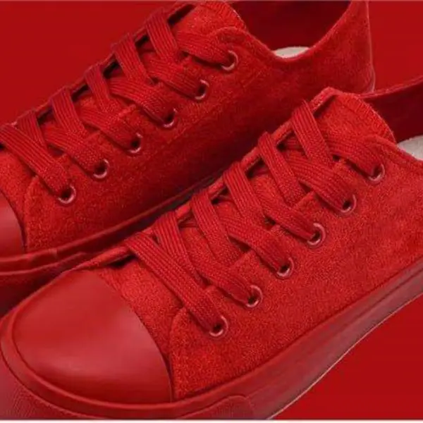 A pair of Wholesale Factory Painted Plush Solid Canvas Shoes—adult sports flat sneakers with rubber soles—side by side on a red background, ideal for OEM ODM customization to match your brand’s unique style.