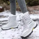Person wearing 2024 Customized LOGO Pattern Style Autumn Winter Trendi Warm Snow Boots Mixed PU Cotton Shoes with white fur lining, standing on snow; only legs and boots visible, highlighting the stylish design.