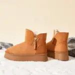 New Design Ladies Warm Winter Snow Ankle Boots for Women—tan suede, side zippers, thick soles, shown on snow with rocks. OEM and ODM custom options available. Fashion platform boots 2025.