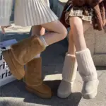 Two women sit outdoors in light skirts, wearing Wholesale Winter New Styles Women Plus Plush Platform Non Slip Snow Boots—Cotton Floette Plush Shoes for Ladies—their legs crossed as sunlight casts soft shadows on the ground.