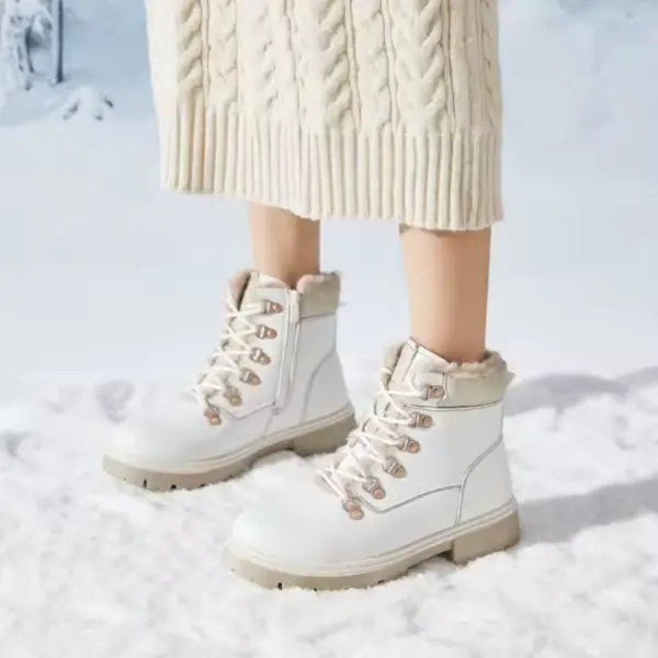 A person stands on snow wearing a cream knit skirt and white Wholesale Ankle Boots Snow Weather for Women Leather Zipper Casual Waterproof Winter Plush Boots.