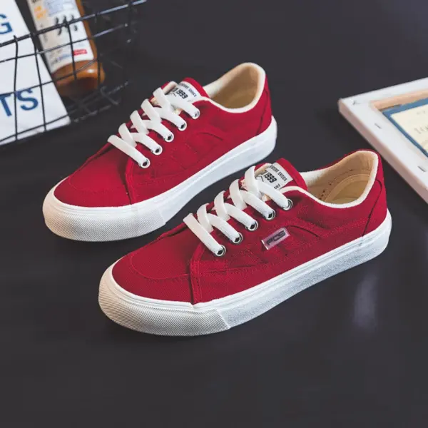 A pair of 2025 Customized Wholesale Retro Street Trending Women Shoes Flat Sneakers in solid color canvas are displayed on a dark surface, highlighting quality perfect for OEM or ODM customization.