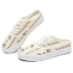 A pair of XRH Wholesale cream canvas slip-on sneakers with white laces, white soles, and a decorative floral and stripe print; customizable with OEM/ODM logo.