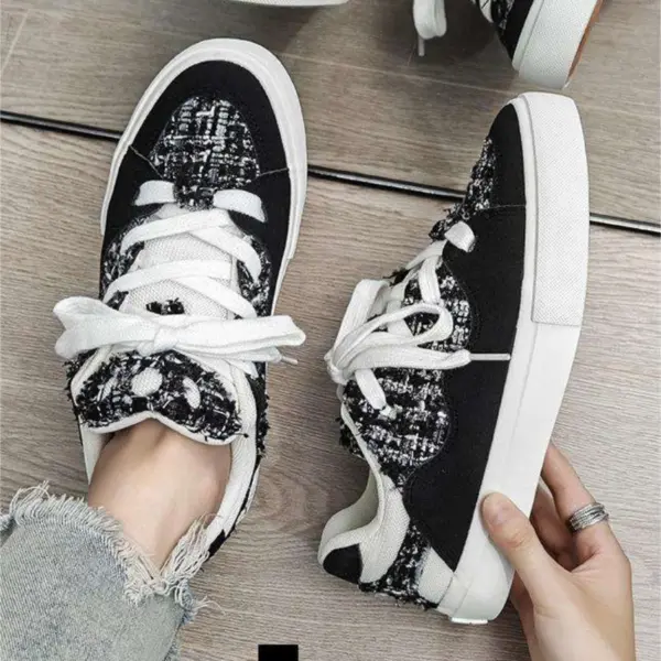 A person in distressed jeans tries on 2025 Wholesale ODM Custom Summer New Canvas Sneakers with lace-up design and solid rubber soles on a wooden floor.