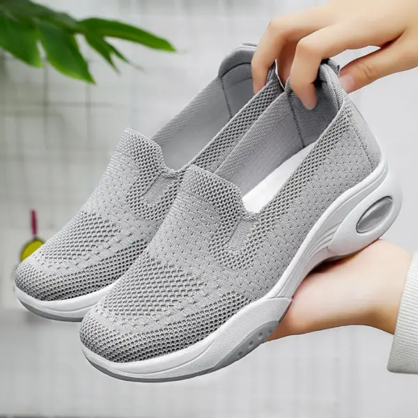 Two hands hold a pair of Fashion Slip on Custom Mesh Sneakers Sports Women Running Shoes 2024 in gray, featuring mesh uppers and thick white soles, against a neutral indoor background.