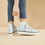 A woman stands on a beige background wearing Hot Sale Zapatos women’s casual blue print canvas sneakers, which feature lace-up design and are customizable for OEM/ODM orders.